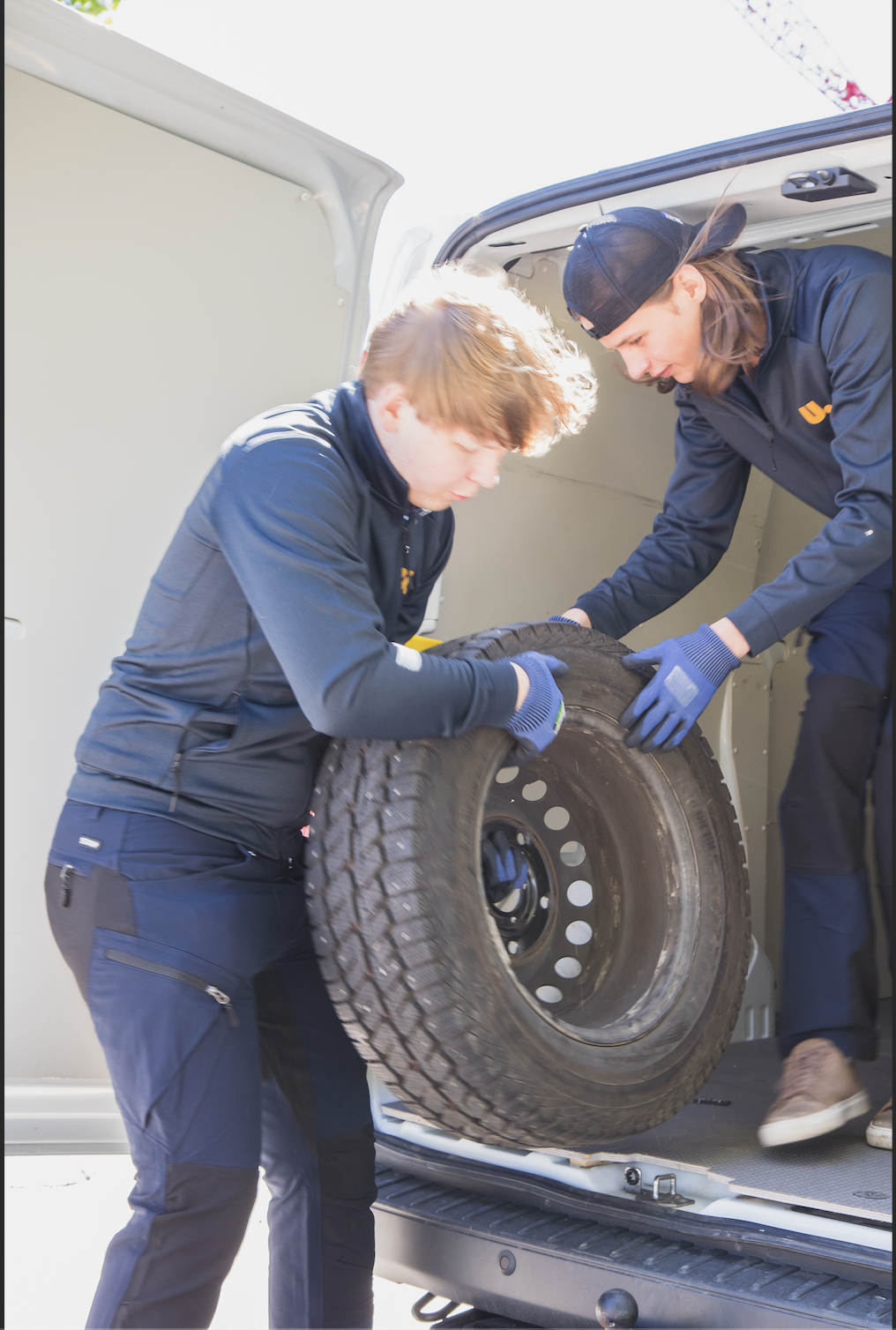 Ungdomskraft-medarbetare lastar däck i skåpbil under flytt med RUT-avdrag