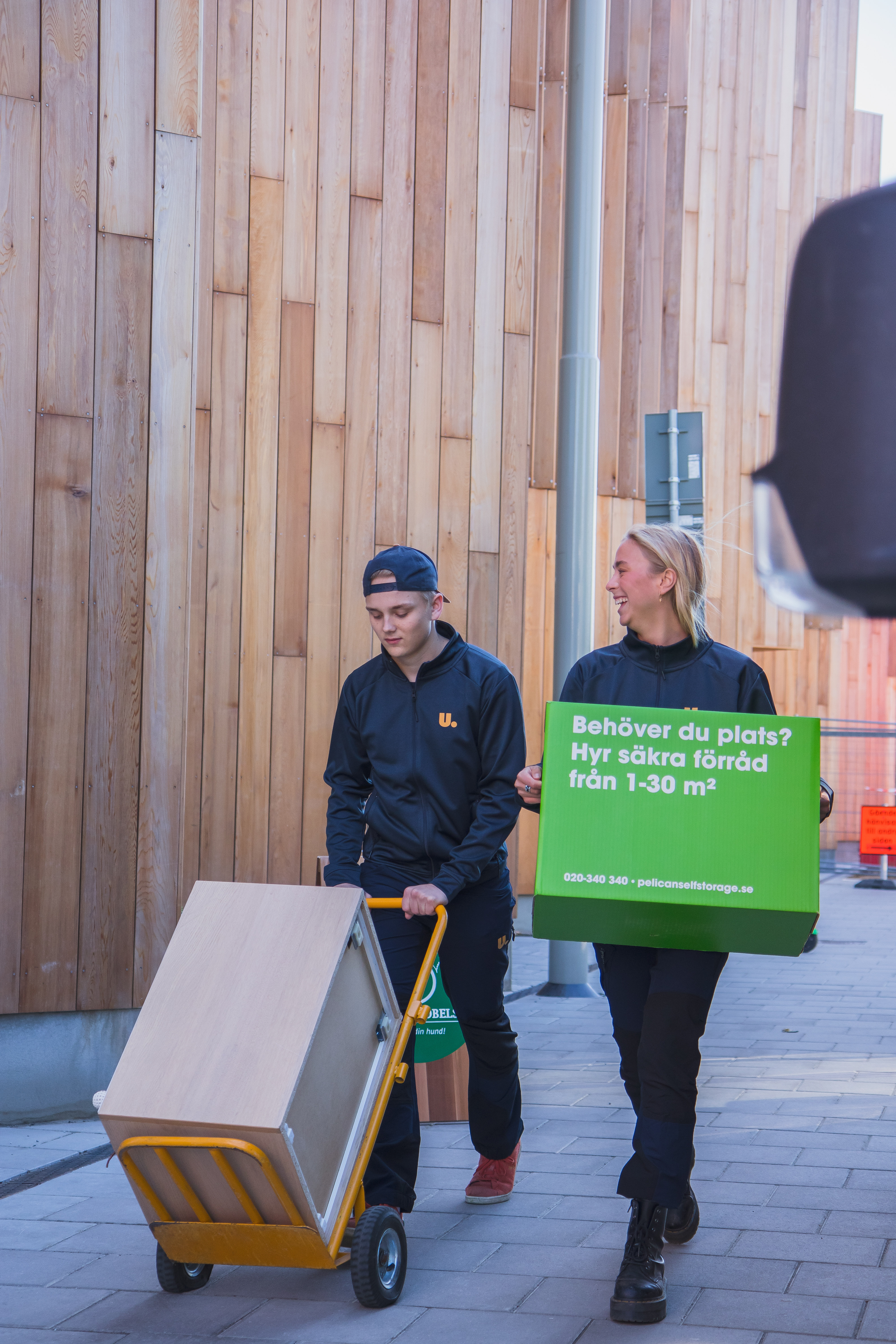 Två Ungdomskraft-medarbetare transporterar möbler med kärra under ett uppdrag